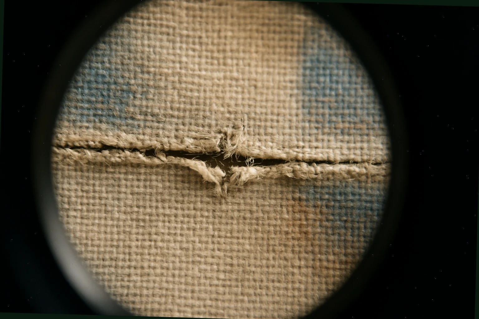Canvas tear aligned with thread-by-thread joins under magnification